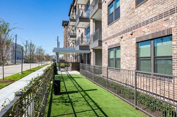 a grassy area with a fence in front of a brick building
